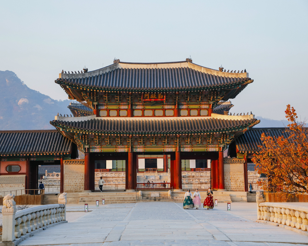 Traditional Korean palace with ornate tiled rooftops and vibrant red columns.