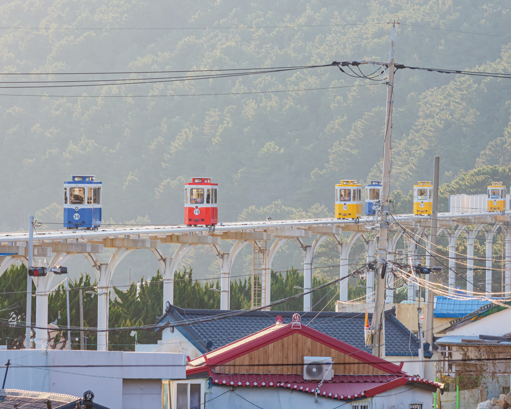 Colorful capsule-style rail cars of the Haeundae Beach Sky Capsule in Busan, South Korea, gliding along the coast.