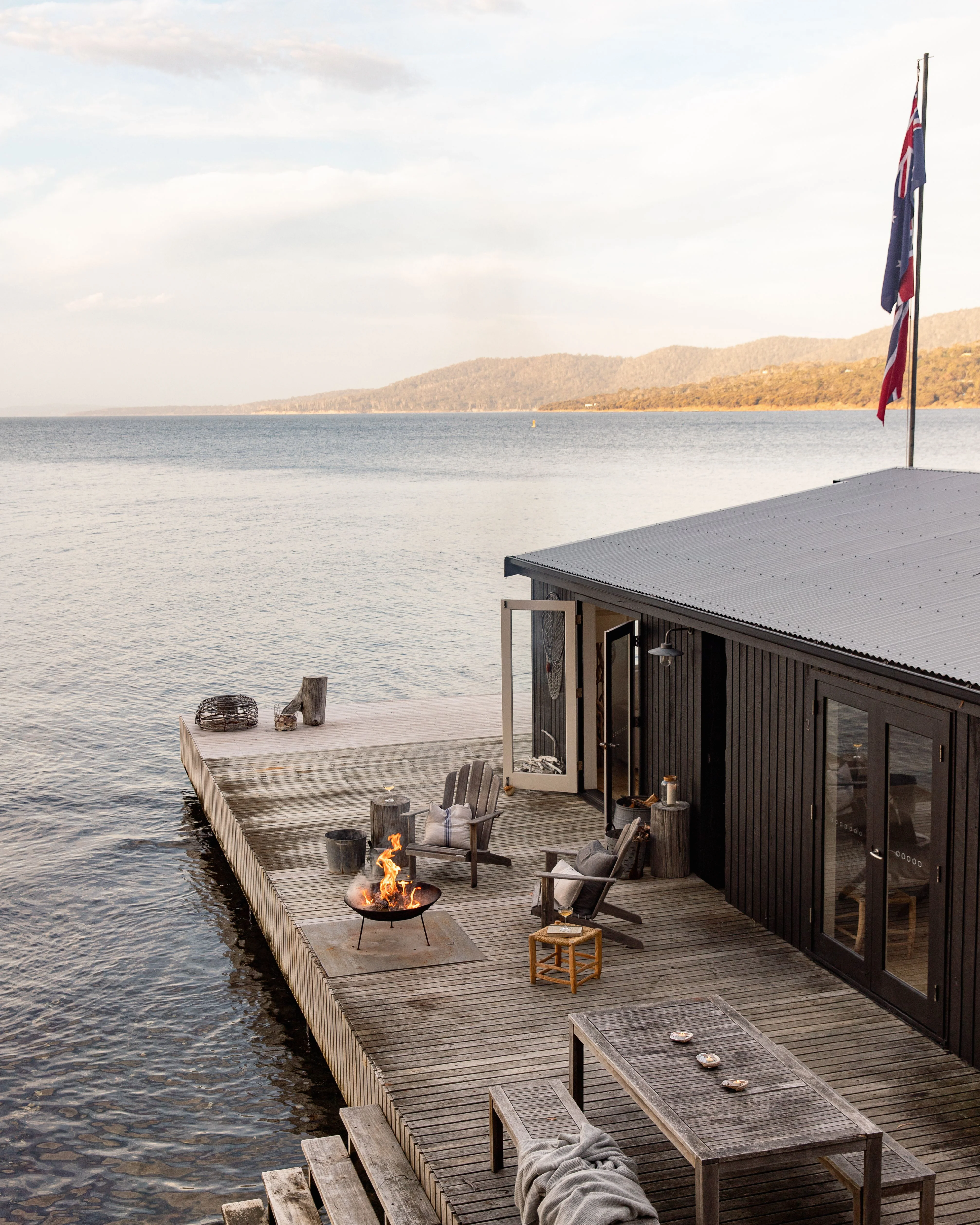 Luxury waterfront deck with fire pit and outdoor seating on Satellite Island near Alonnah Tasmania in the D’Entrecasteaux Channel