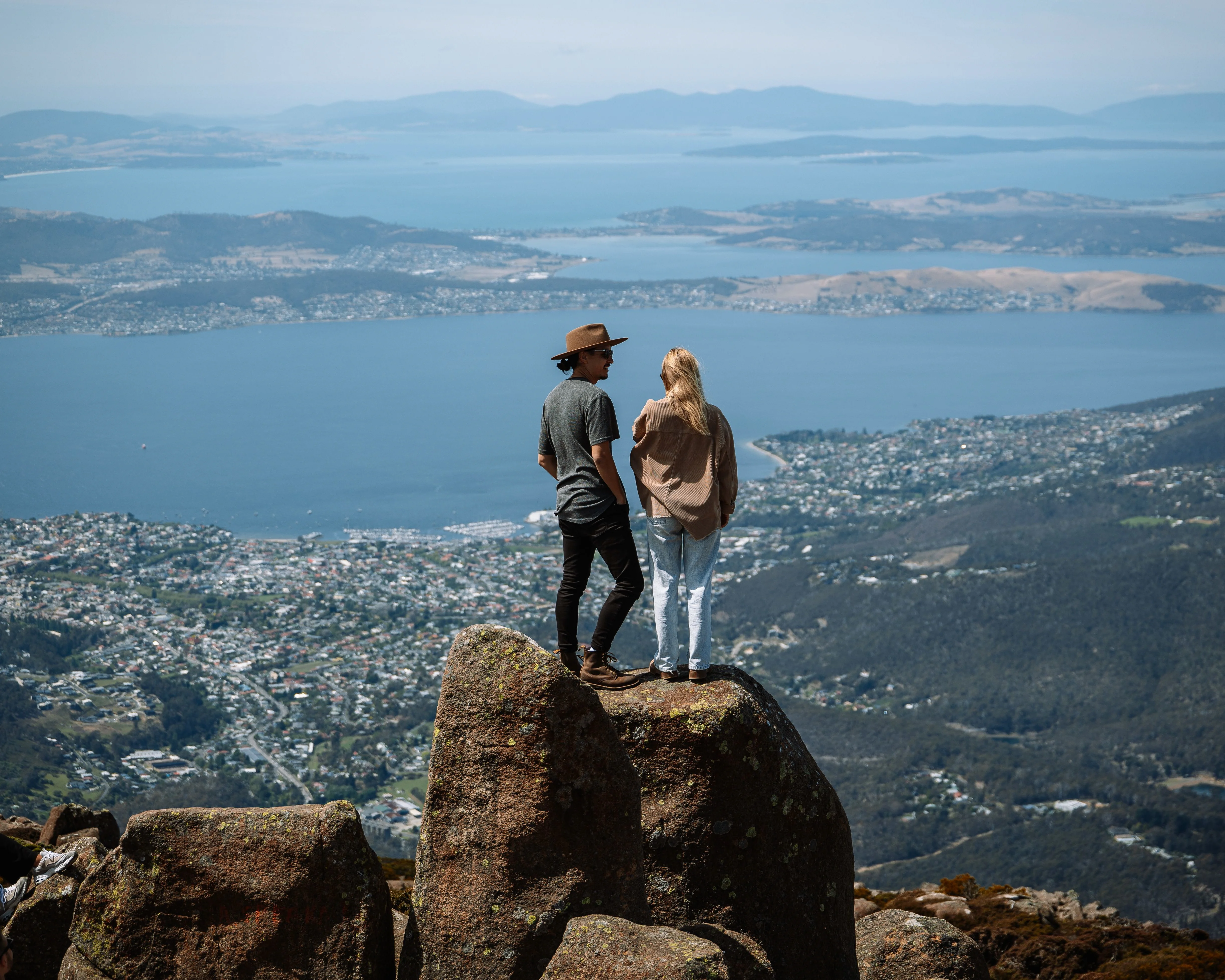 Couple standing on Mount Wellington summit Hobart Tasmania with sweeping city views
