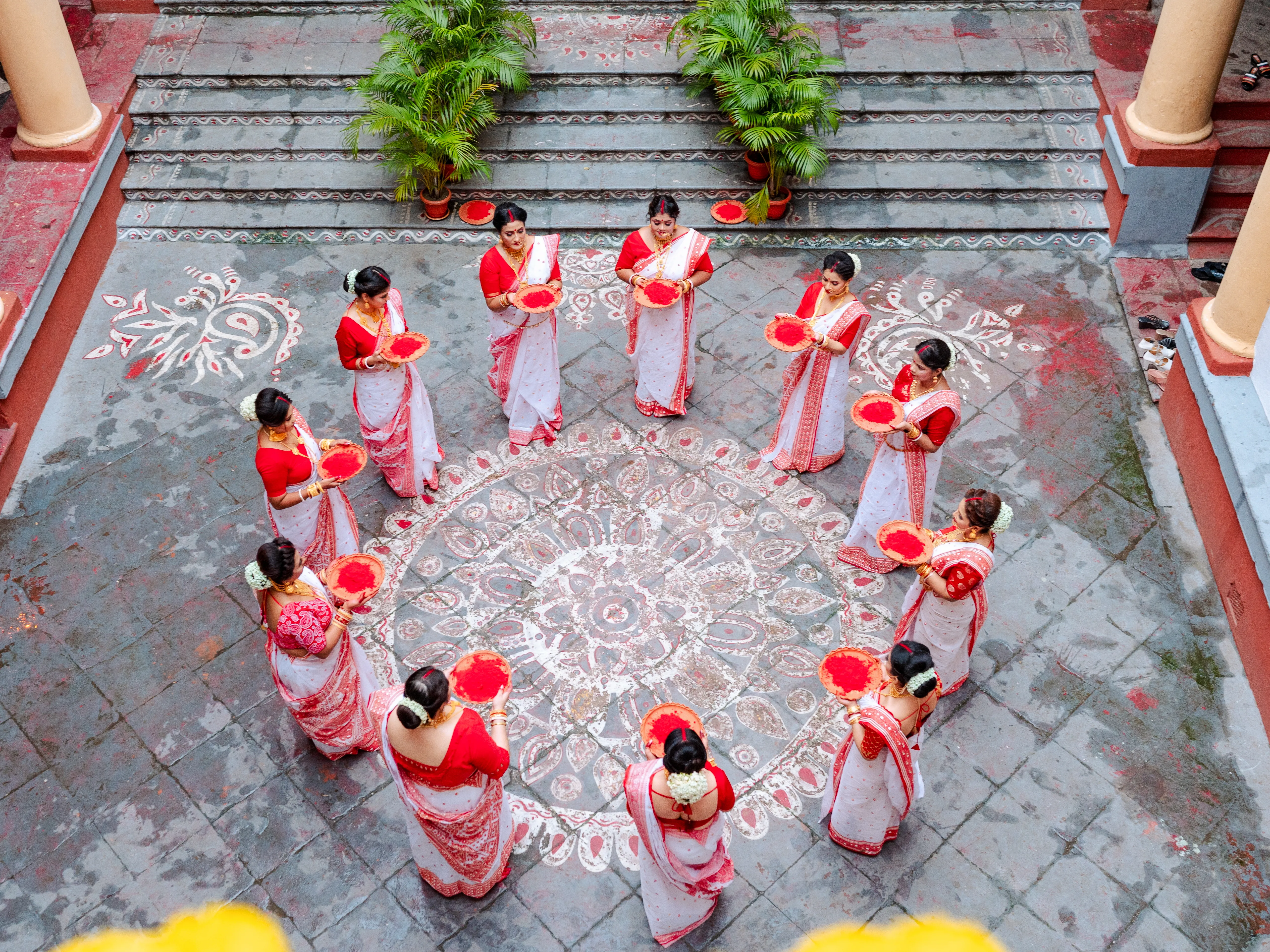 Traditional Durga Puja ceremony with participants gathered around a decorative rangoli design.