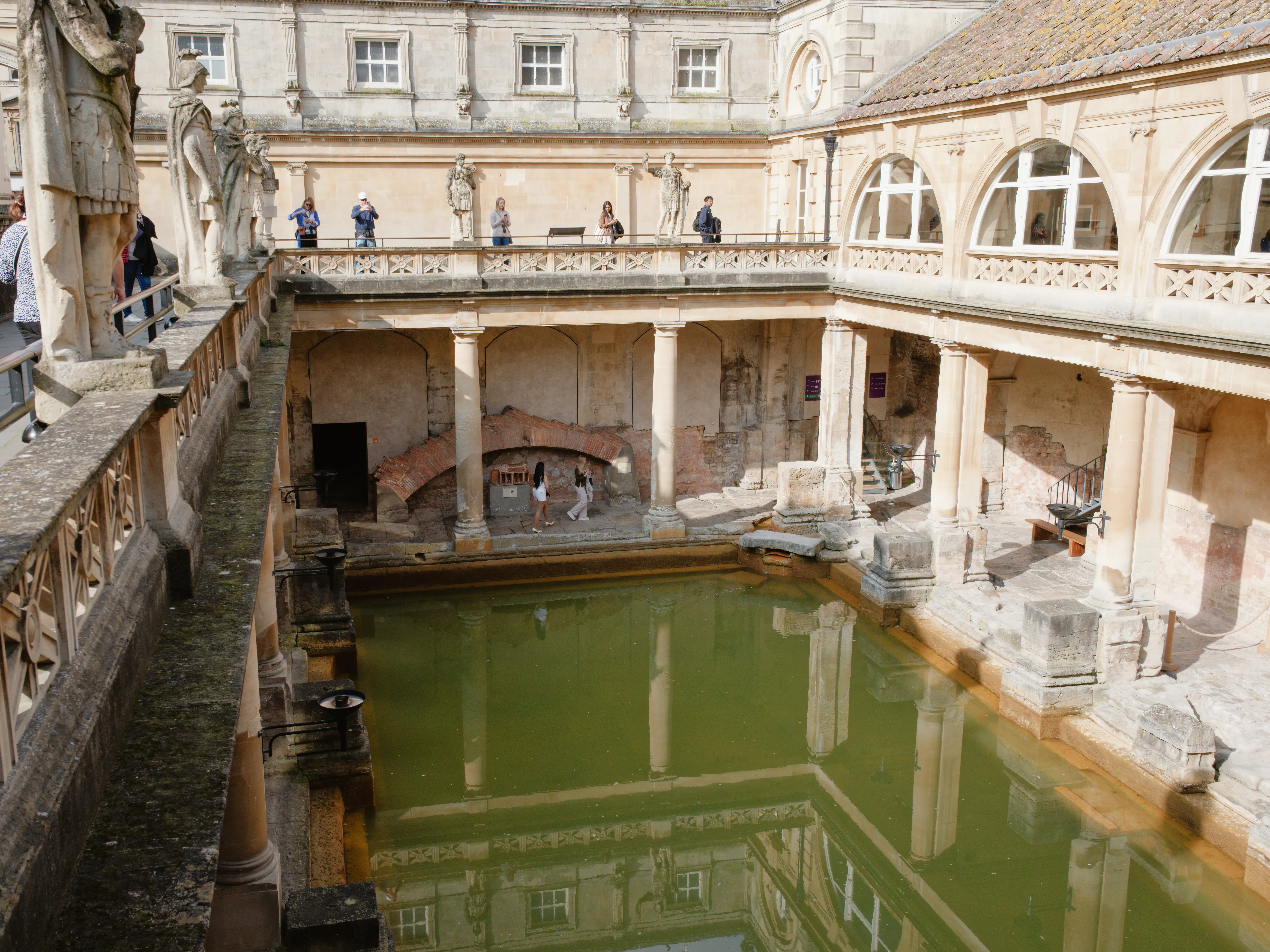 Ancient Roman Baths in Bath with stone columns and green thermal waters, a famous historical day trip from London.