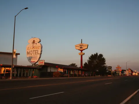 Vintage Route 66 motel signs along a quiet American roadside at sunset under a clear sky