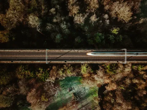 Aerial view of a train traveling through a forest landscape, highlighting scenic transport on day trips from London.