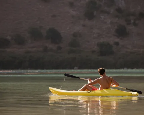 Adventure traveller kayaking on a lake, representing activities that may be covered by adventure and sports travel insurance.